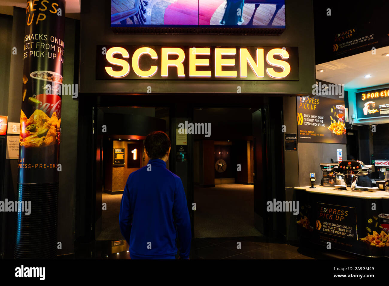 A young boy with ADHD, autism, Asperger syndrome walks towards the cinema screens at VUE in Newcastle to watch a movie, film Stock Photo