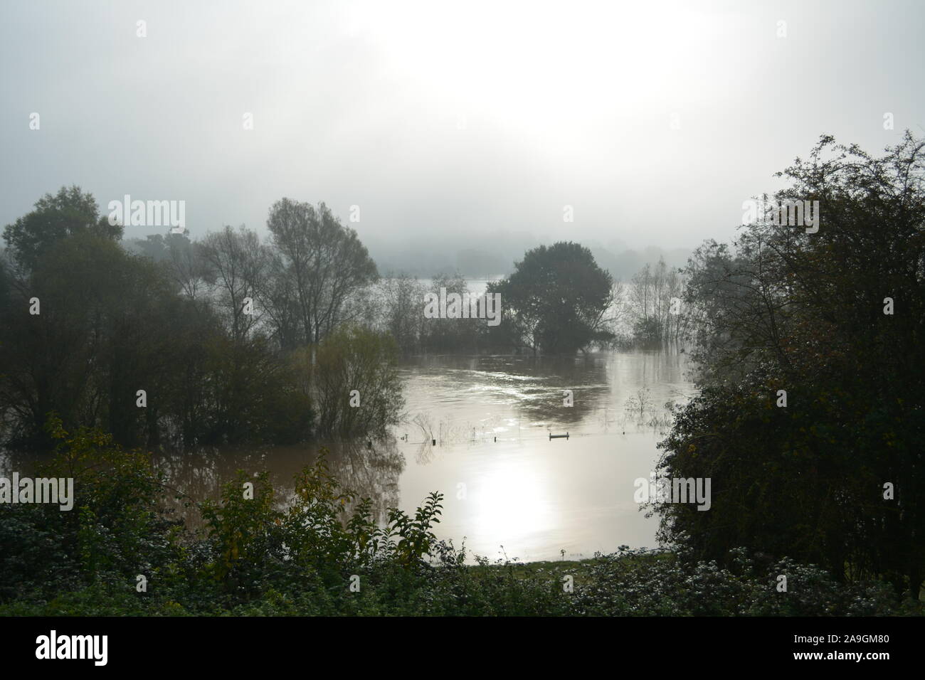 Flood waters from the River Wye near Ross on Wye Herefordshire with sun trying to break through rain clouds re climate change winter river defences Stock Photo