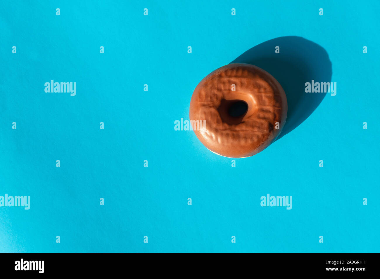 Chocolate frosted donut on bright blue background Stock Photo