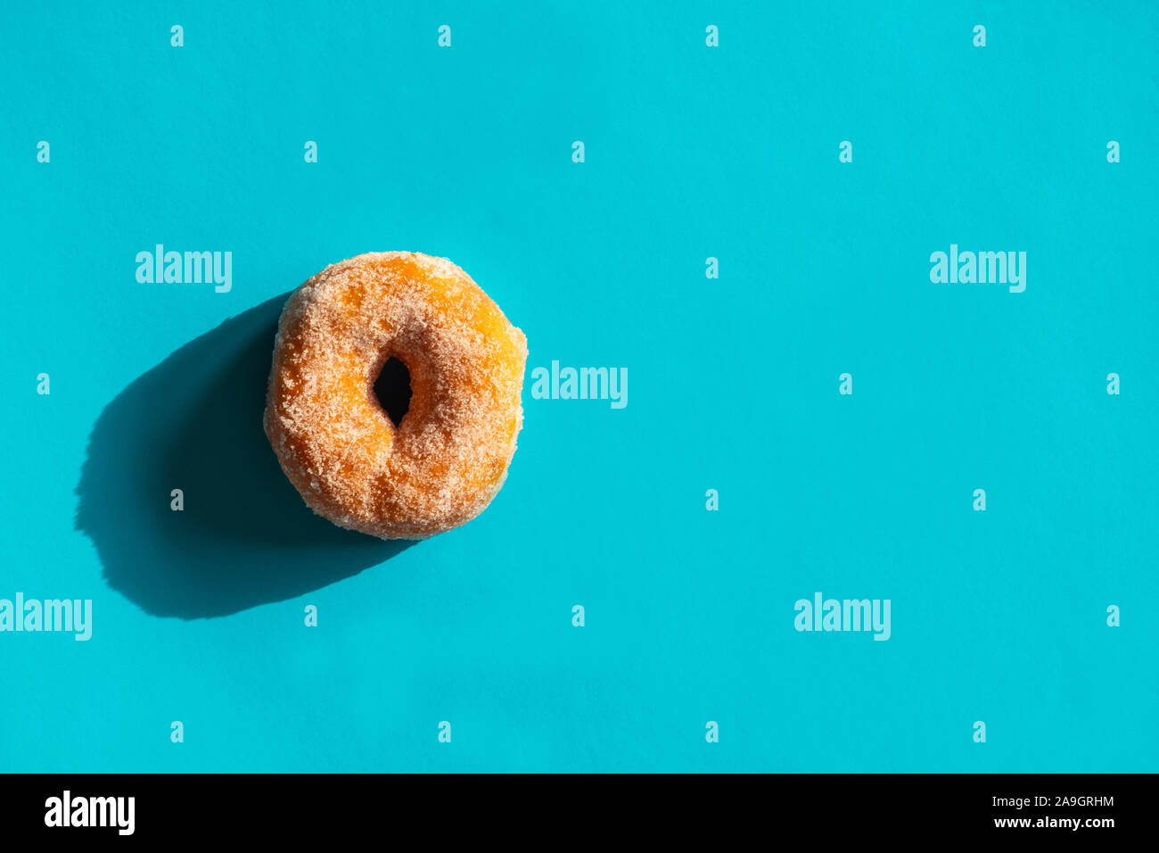 Classic fried sugared donut on bright blue background Stock Photo