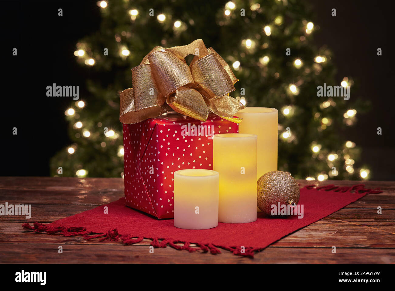 Winter holiday Christmas still life of glowing electric candles, wrapped gift and Christmas tree ornament Stock Photo