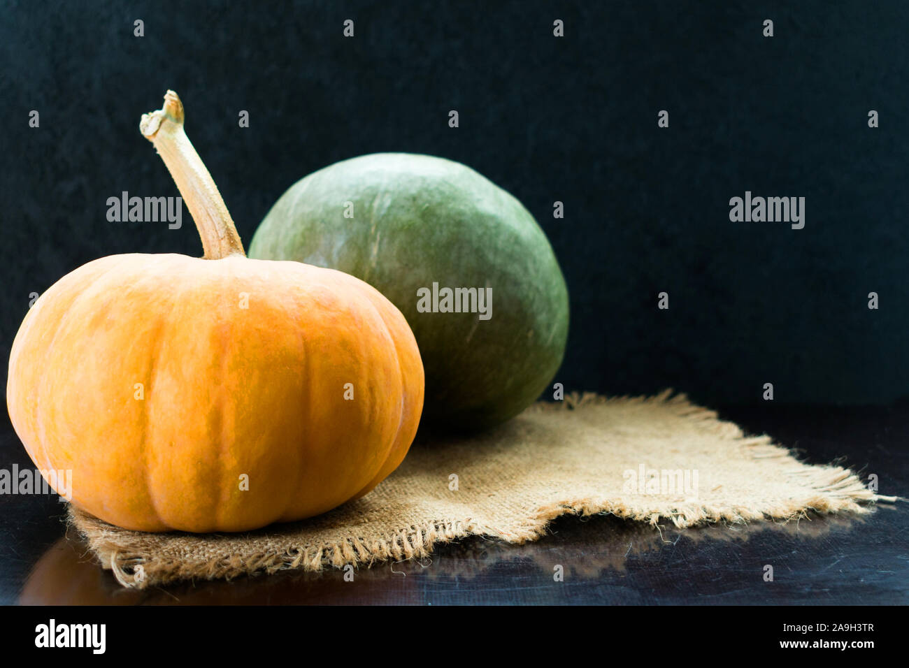 Two green and orange pumpkins on a black background. Copy space. Stock Photo