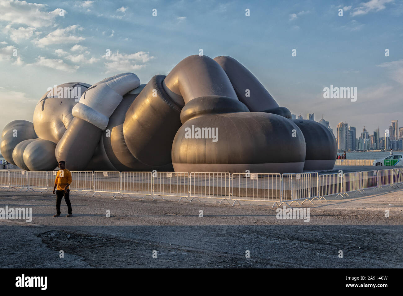 KAWS Holiday art installation in Doha Cor niche , Qatar Daylight view with clouds in sky Stock Photo