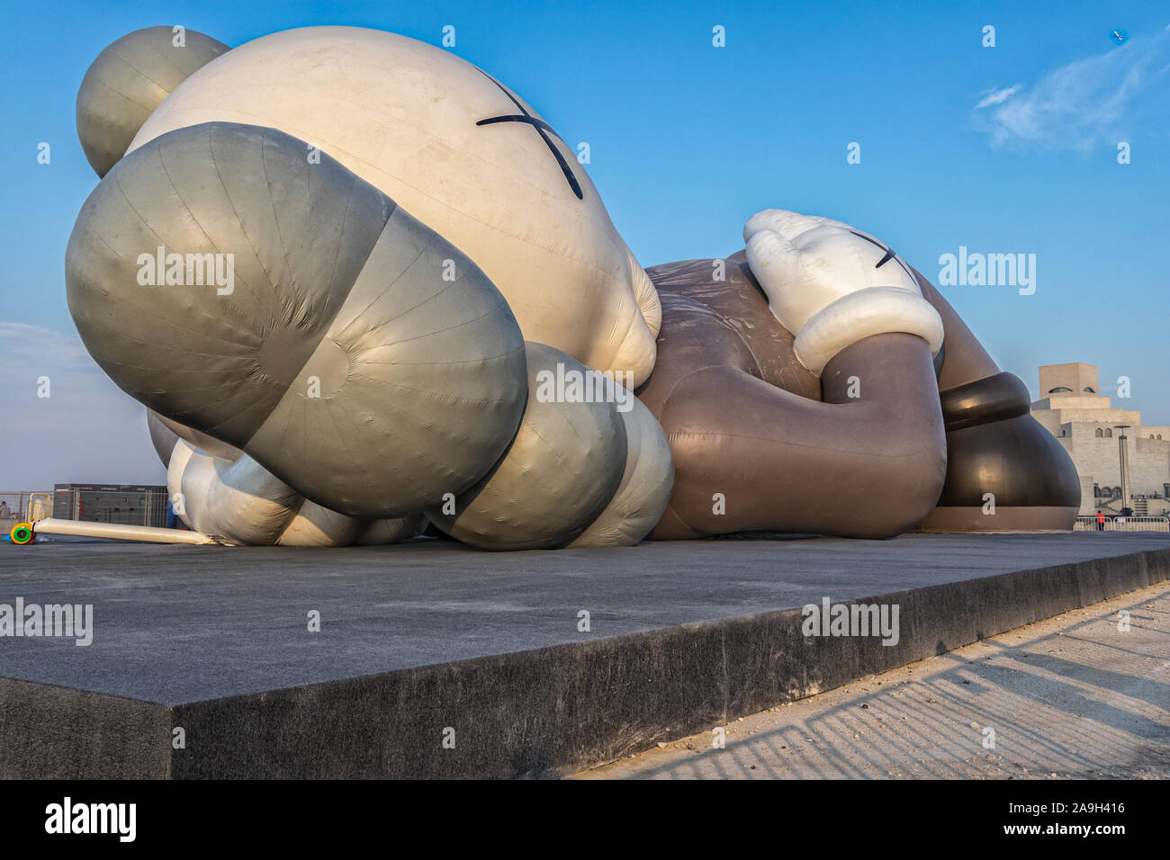 KAWS Holiday art installation in Doha Cor niche , Qatar Daylight view with clouds in sky Stock Photo