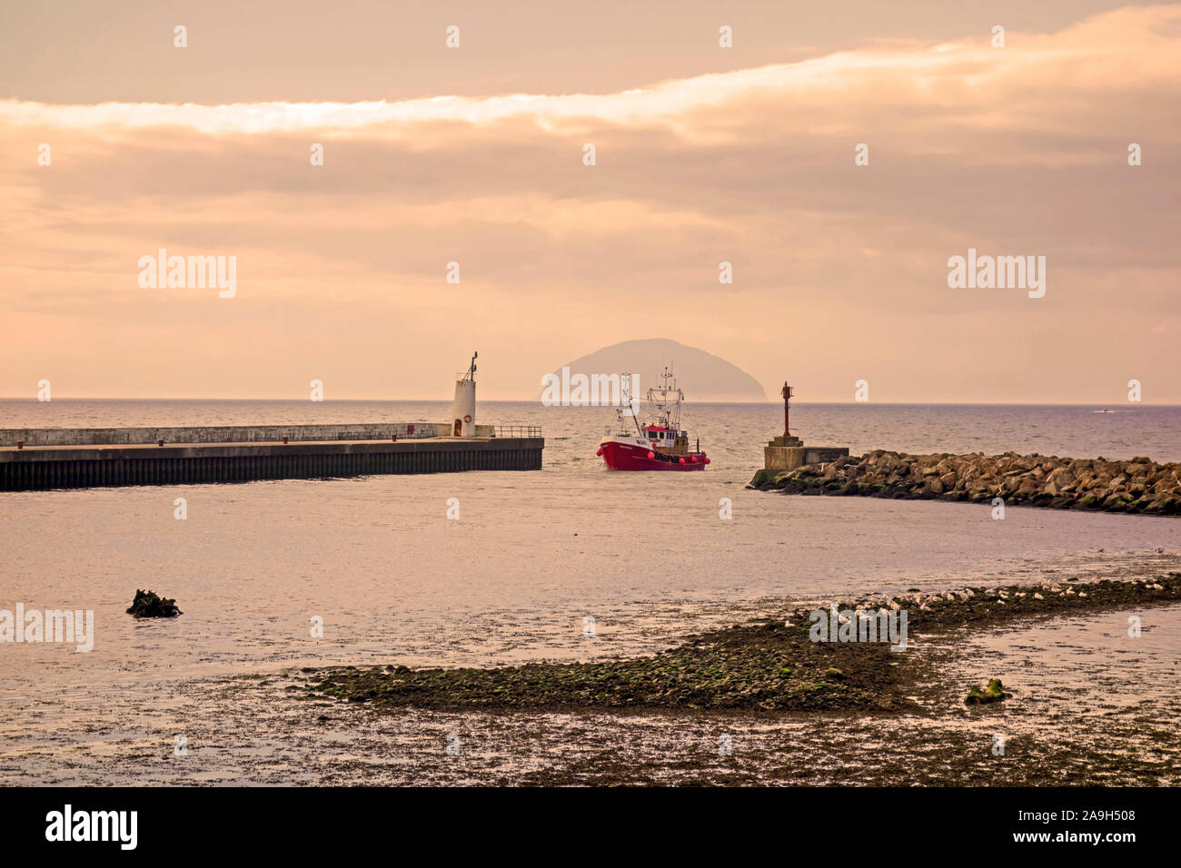 A fishing boat entering the harbour at Girvan in South Ayrshire, Scotland, with Ailsa Craig in the distance. Stock Photo