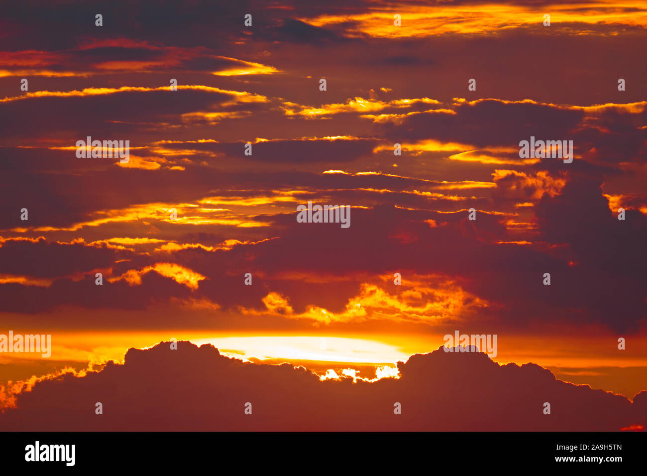 Bright sun against background dark heavy clouds and red sky Stock Photo