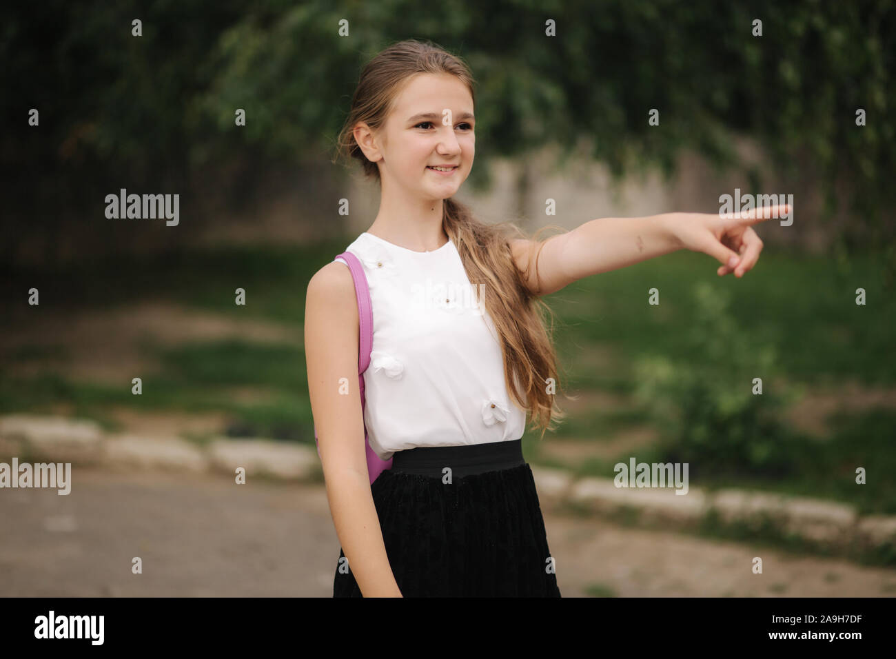 Young girl walking in the park with backpack Stock Photo - Alamy