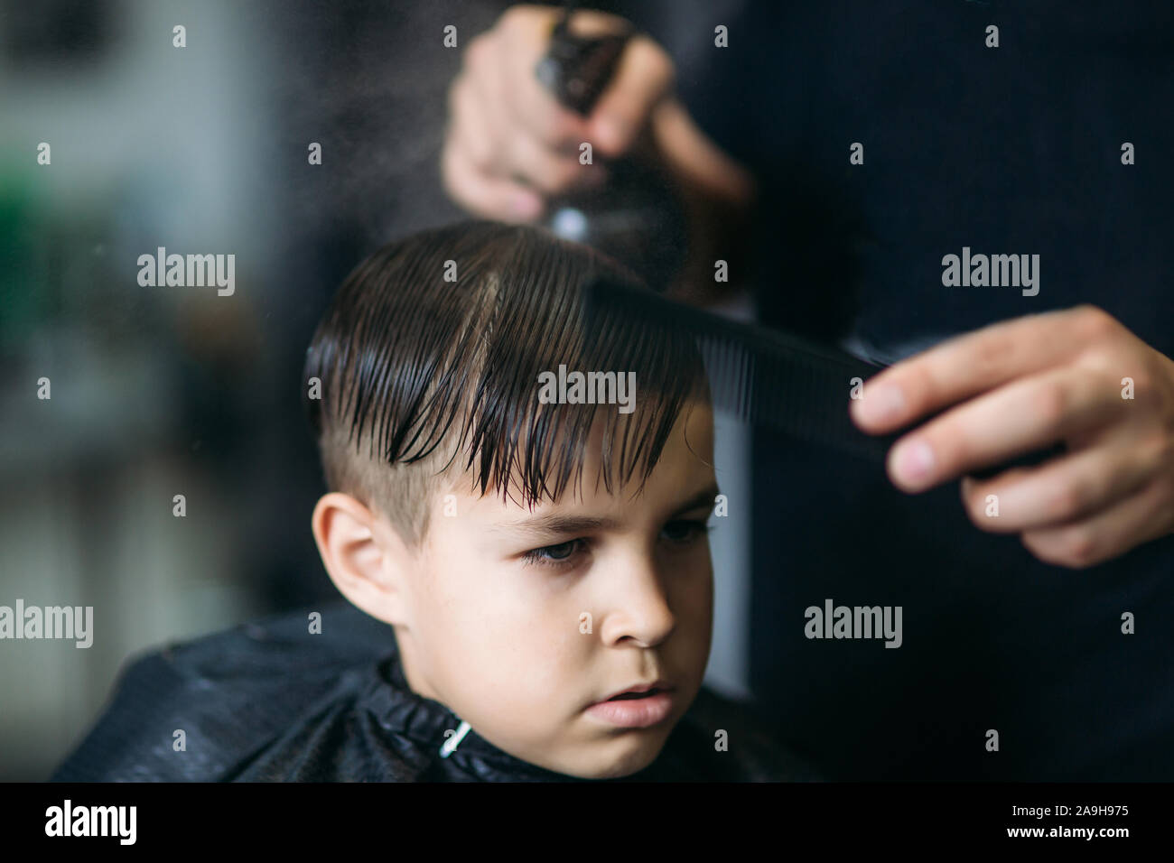 The boy getting haircut by scissor in Barber use scissor