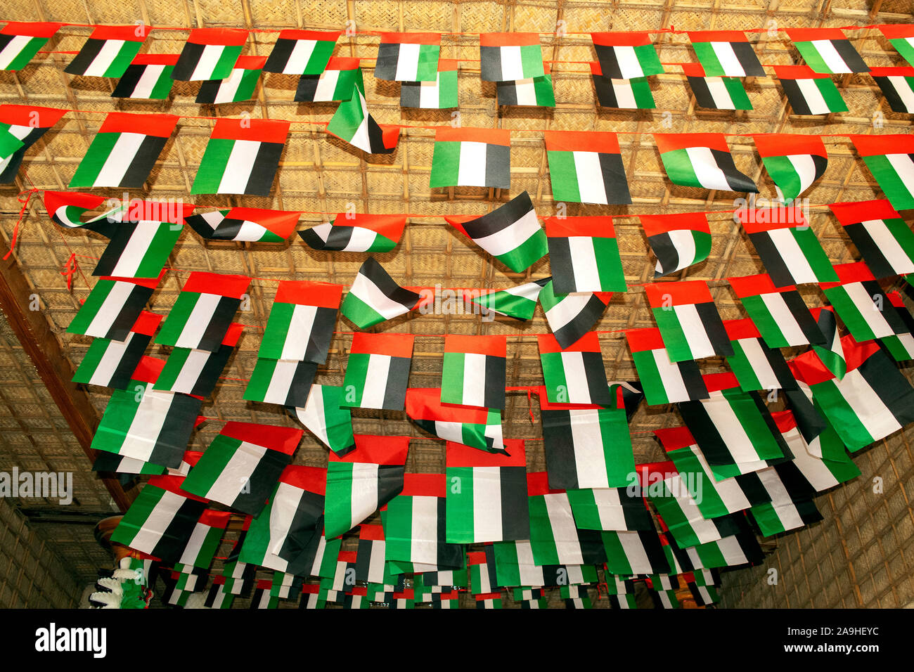 Many UAE flags and decorations on old Dubai city background. Old Dubai