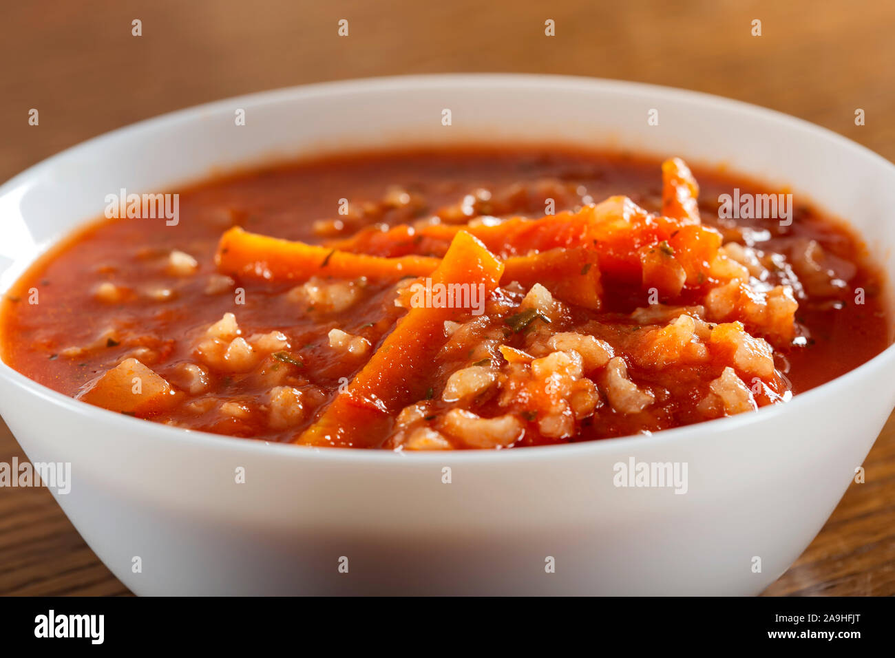 Tomato creamy soup with carrot and rice in a white bowl Stock Photo