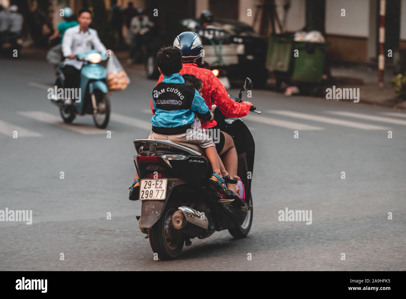Hanoi, Vietnam - 18th October 2019: Parents take their children to school on a moped in the busy streets of Hanoi without any protection or a helmet Stock Photo