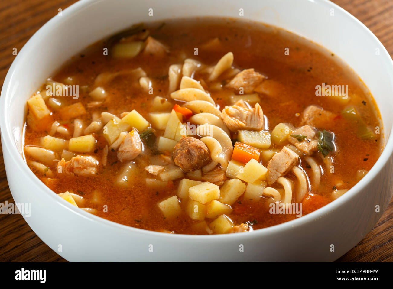 Soup with fusilli, chicken meat and vegetables in a white bowl Stock Photo