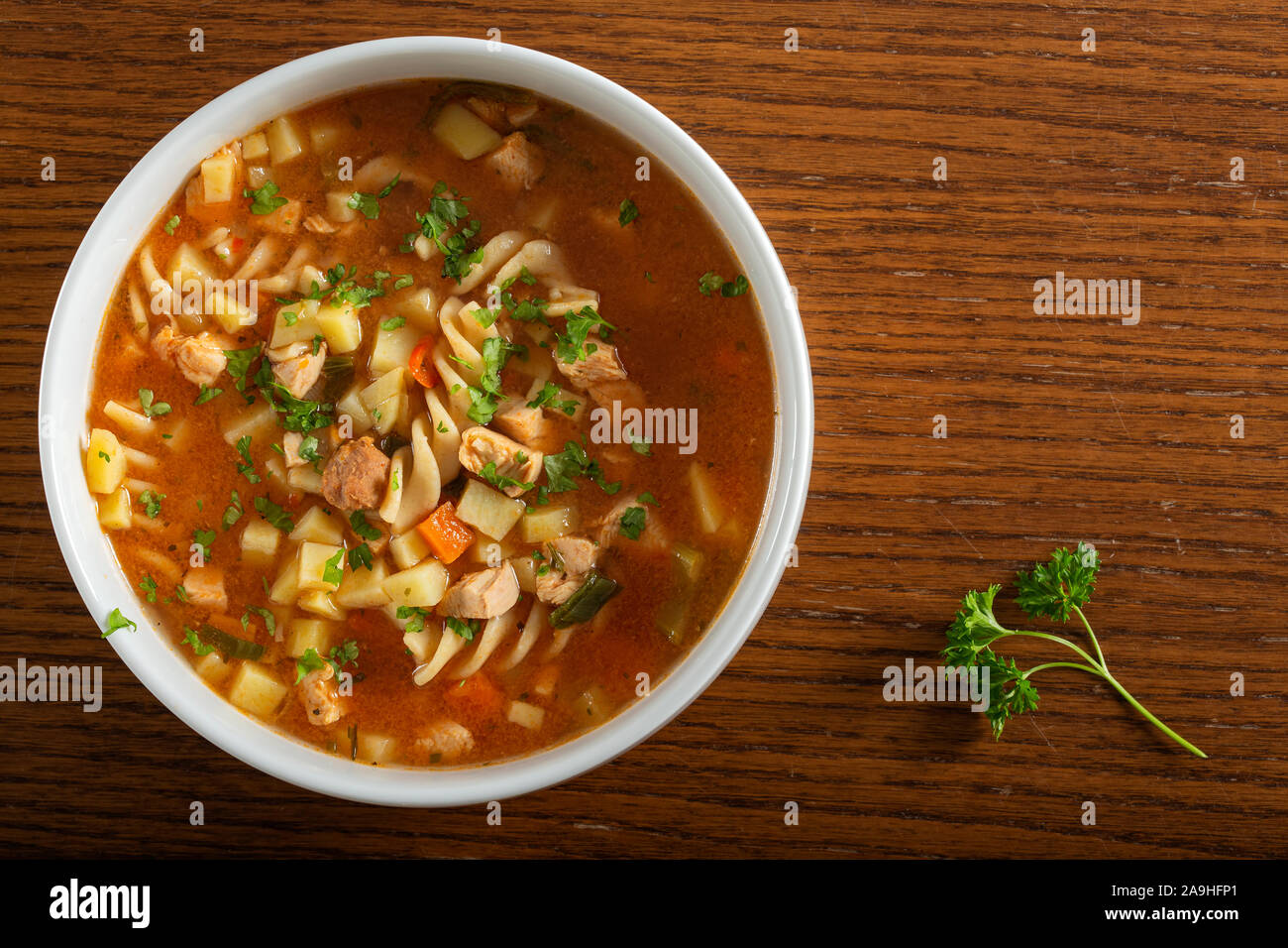 Soup with fusilli, chicken meat and vegetables in a white bowl - top view Stock Photo