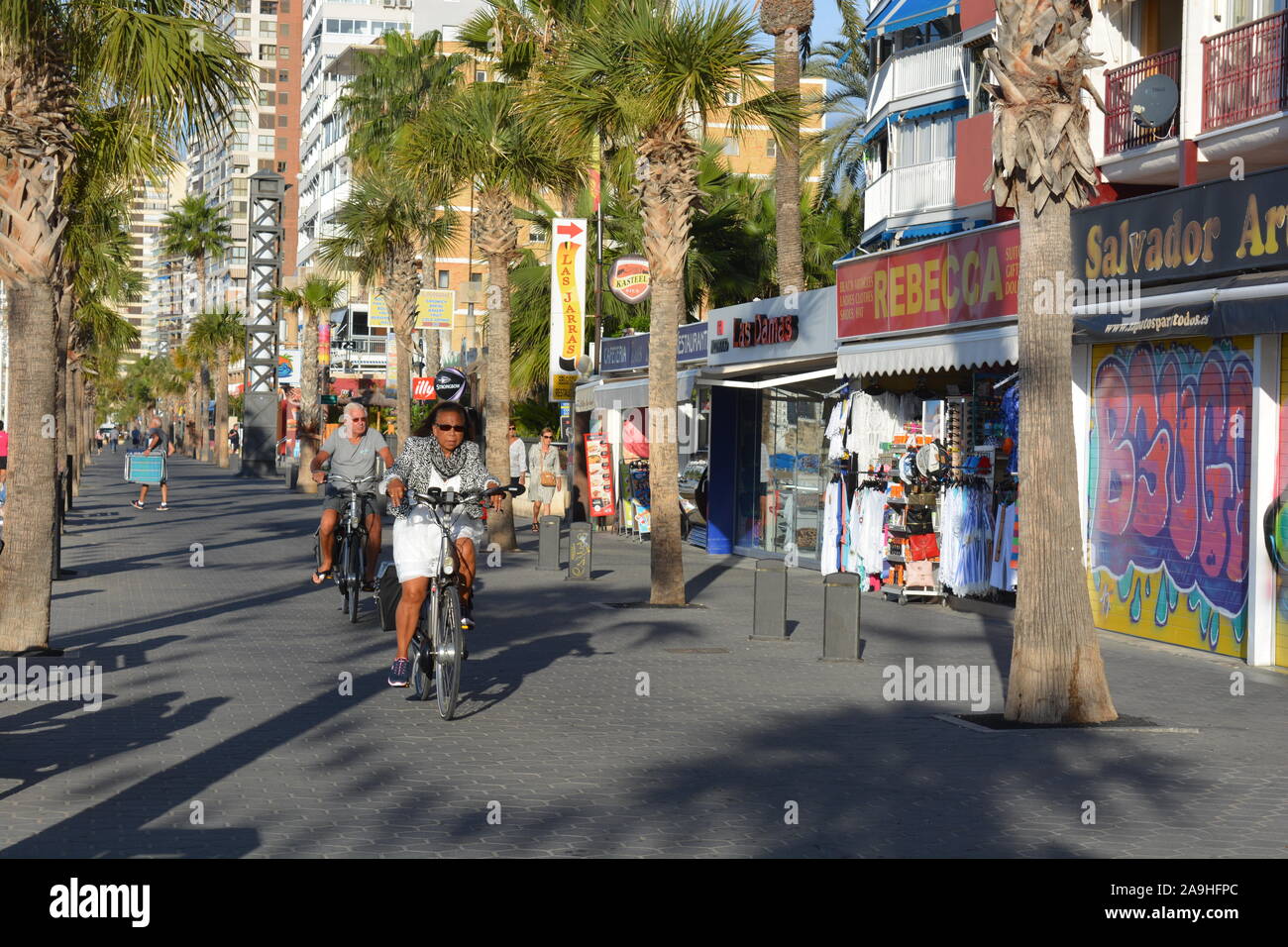 Seniors cycling on the promenade of Playa Levante beach in the early morning, Benidorm, Alicante Province, Spain Stock Photo