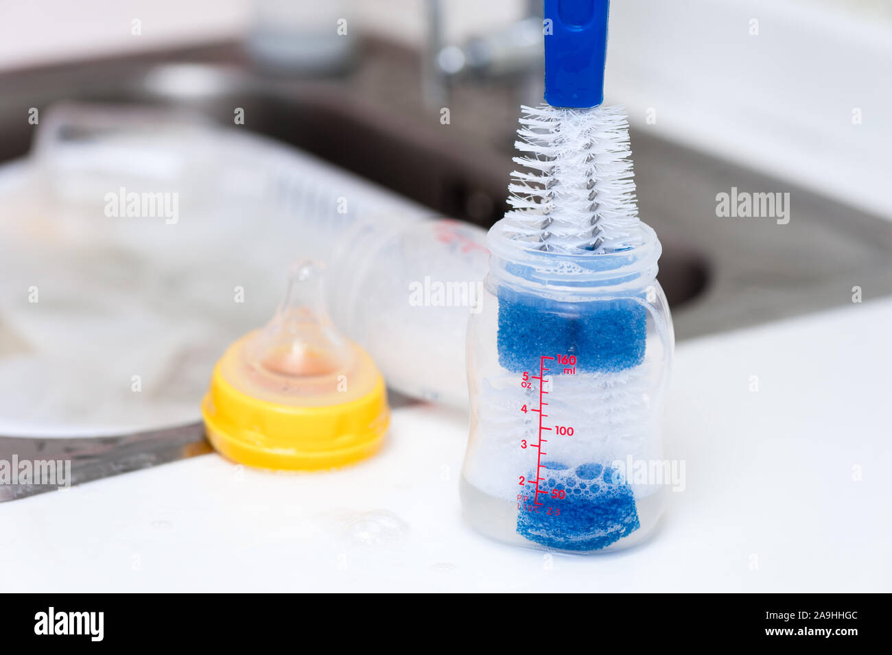washing baby bottles and nipples with soft bottle brush and dishwashing