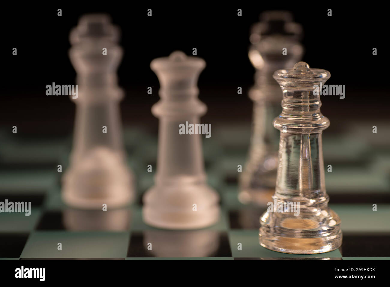 Pieces on a glass chess board - King, Knight, Queen Stock Photo