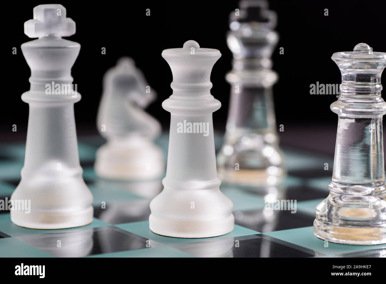 Pieces on a glass chess board - King, Knight, Queen Stock Photo