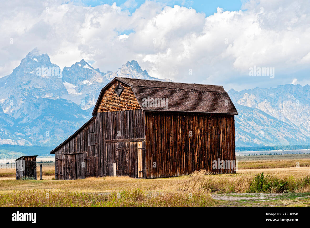 Old wooden barn with in field with mountains beyond. Stock Photo