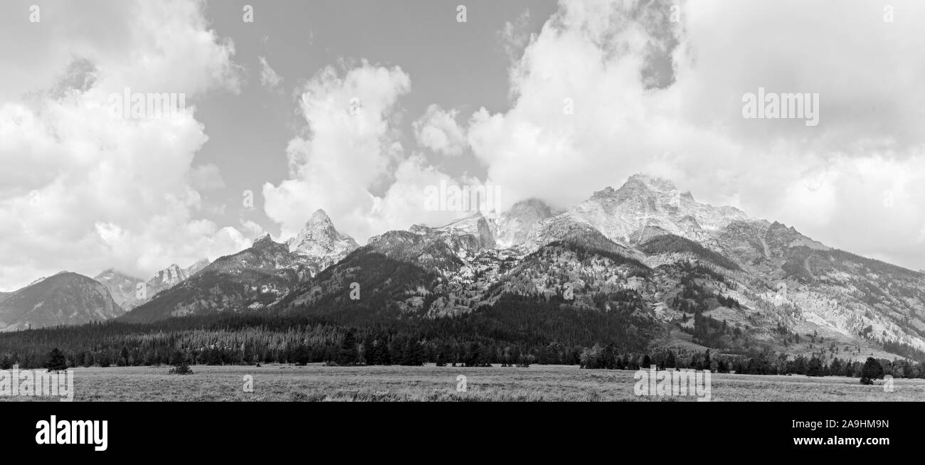 Black and white panoramic of Grand Teton mountains with white fluffy clouds above. Stock Photo