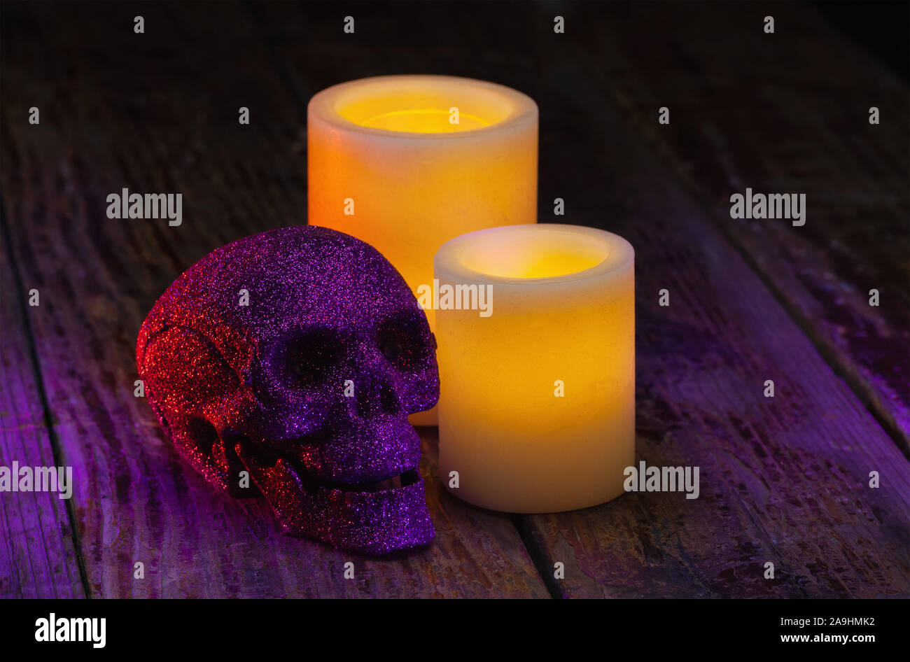 Halloween holiday still life of yellow electric wax candles and an artificial skull Stock Photo