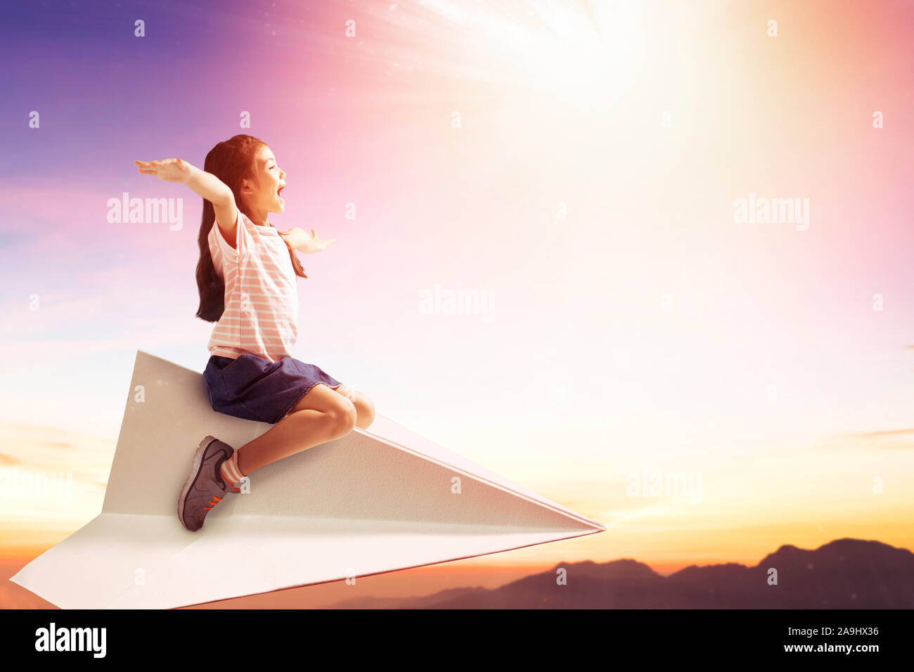 happy little girl on paper plane and flying in the sky Stock Photo - Alamy
