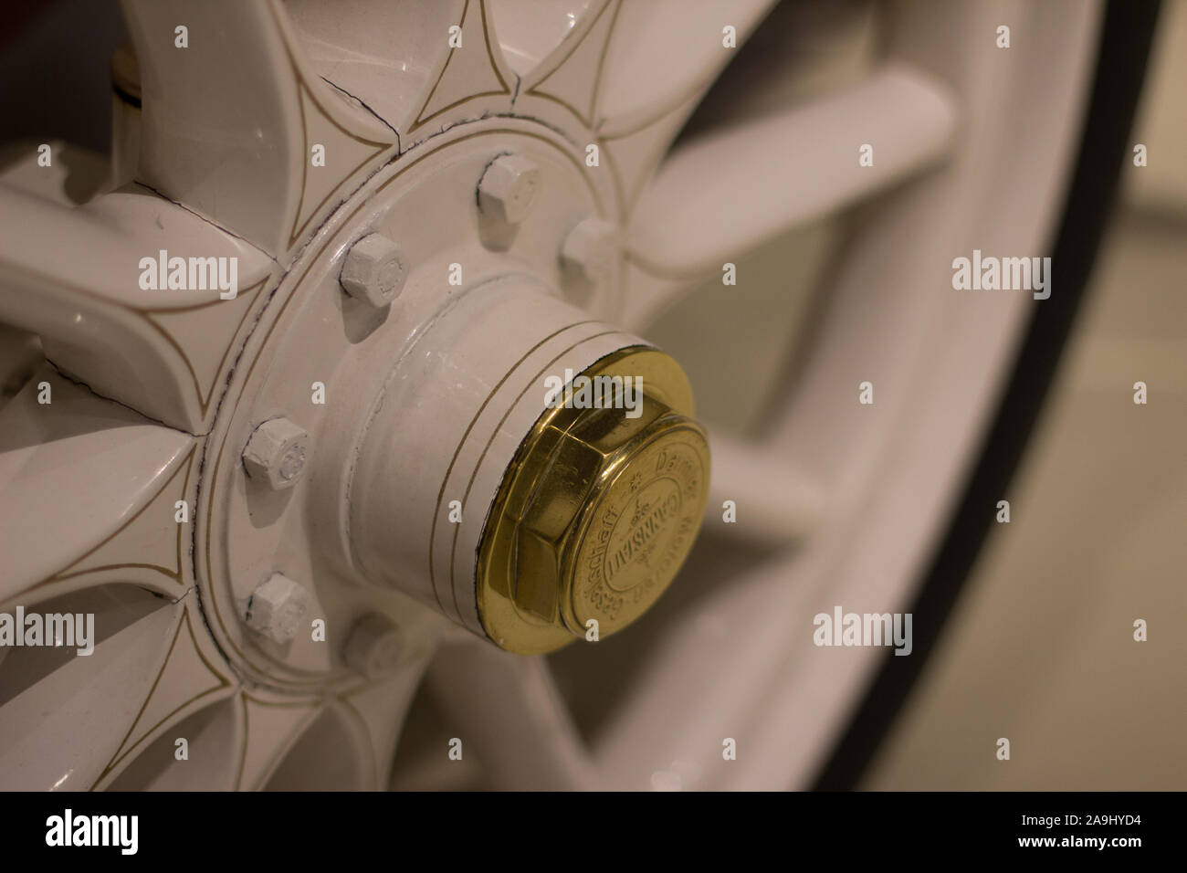 Front view, white wood spokes on a white wall tire with brass center