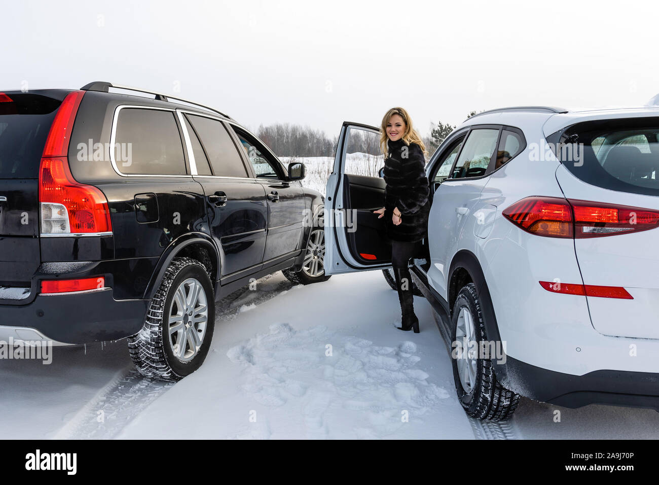 The blonde woman gets out of the white suv car and looks back. Stock Photo