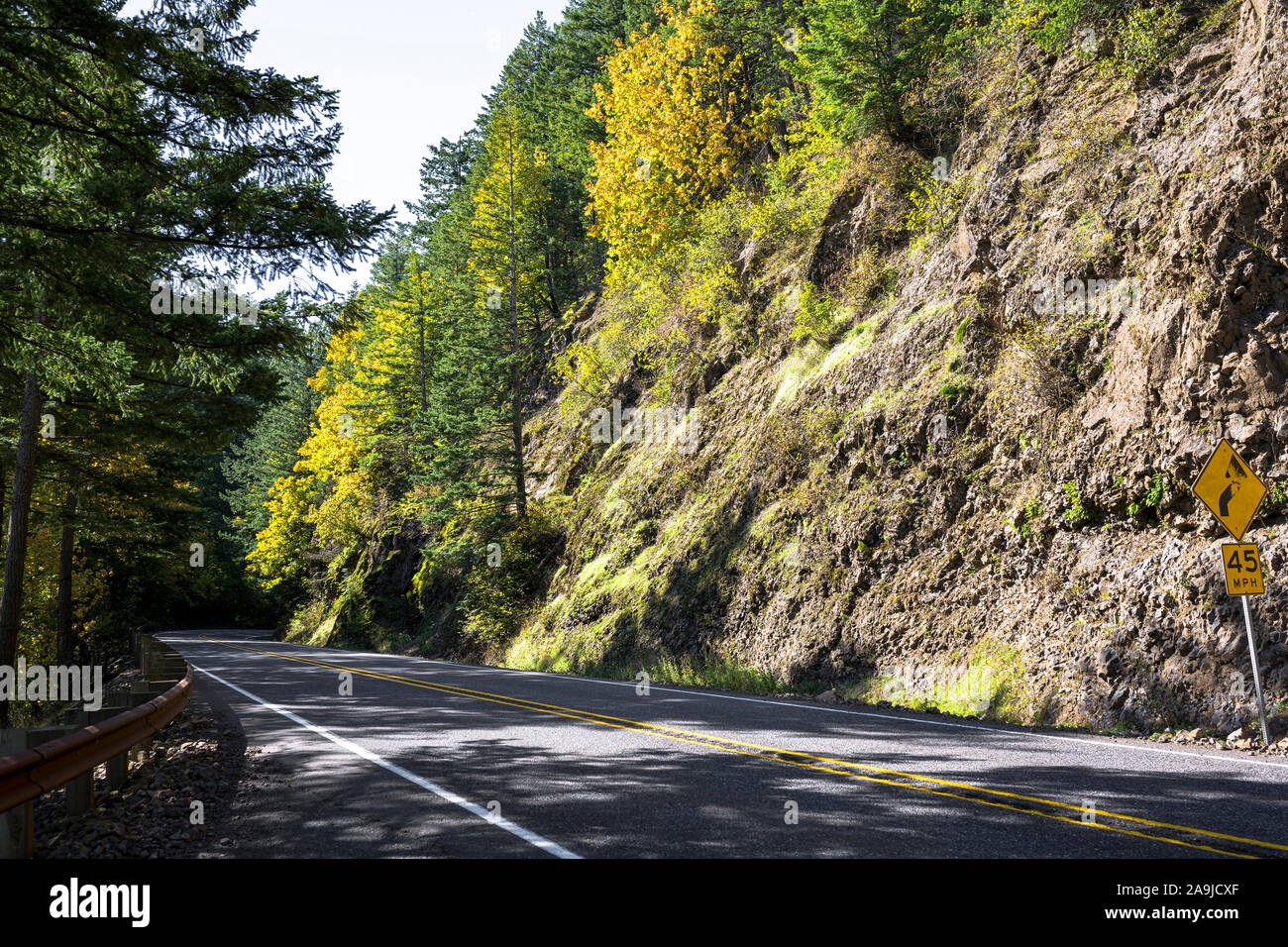 A mesmerizing landscape that attracts tourists with a winding road with road sign around a rock cliff on one side and an abyss on the other side in th Stock Photo