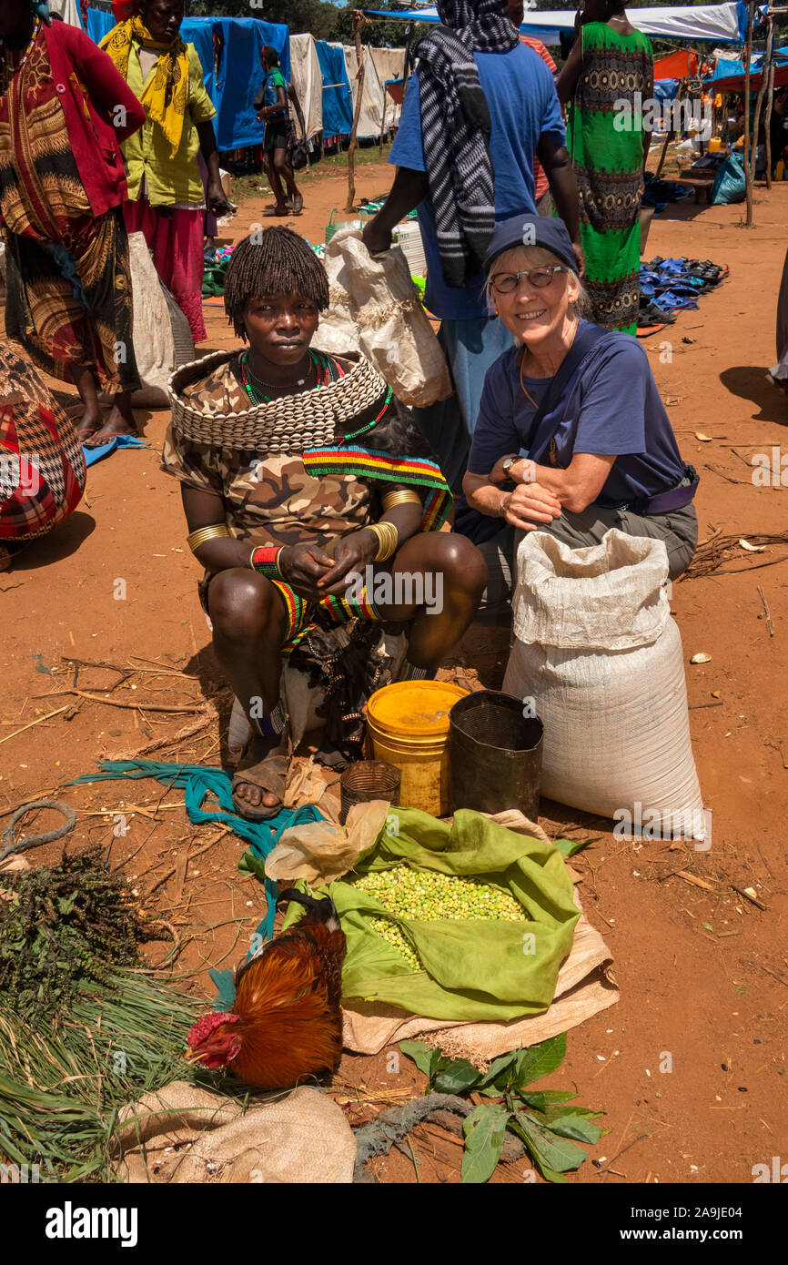 Ethiopia, South Omo, Key Afer, Thursday Market, Banna Tribal woman trader with cowrie shell collar with senior western tourist Stock Photo