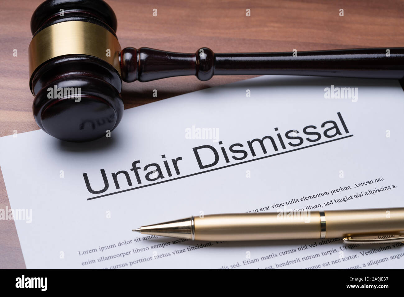 Documents Of Unfair Dismissal With Gavel And Pen On Wooden Desk In A Courtroom Stock Photo