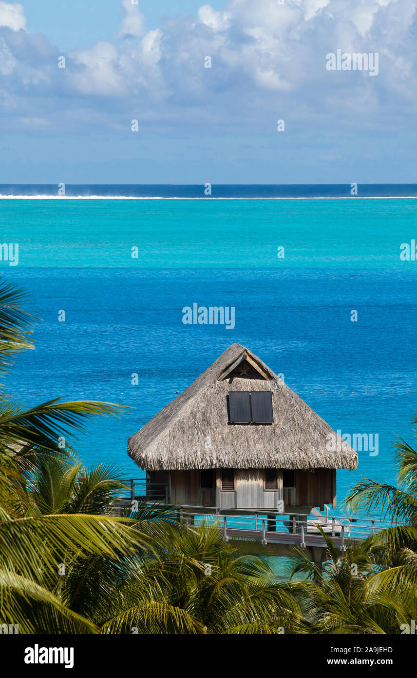 house over the water of a blue tropical sea with a thatched roof in a ...