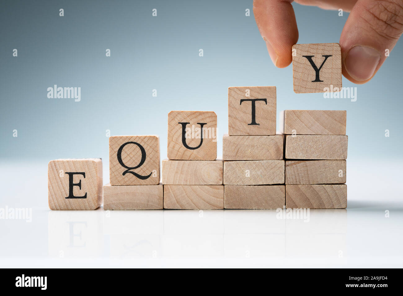 Human Hand Arranging Stack Of Wooden Blocks In A Row Showing Equity Text Stock Photo