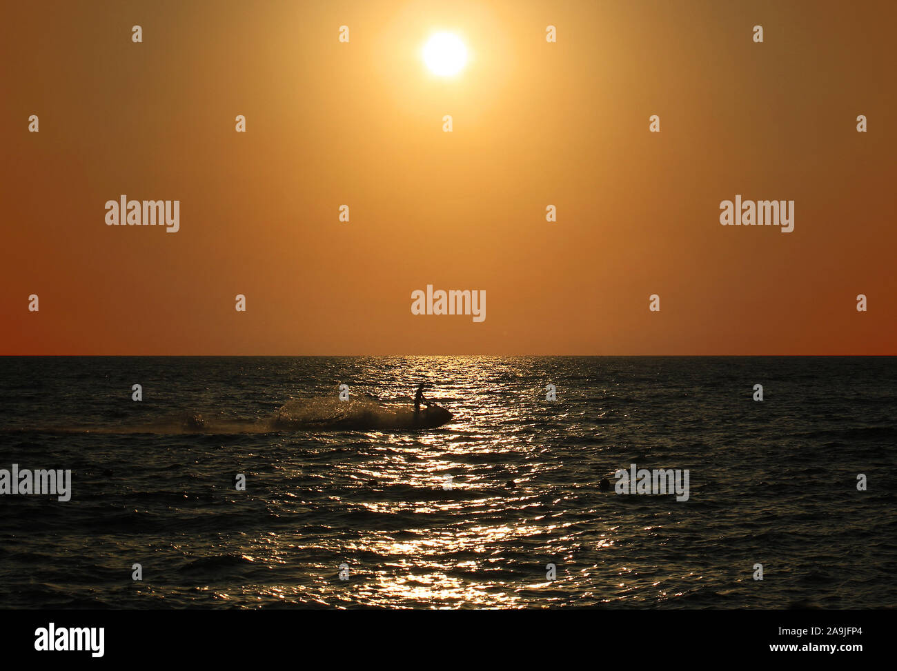 A jet skier riding through the sunset in the Mediterranean sea. Stock Photo