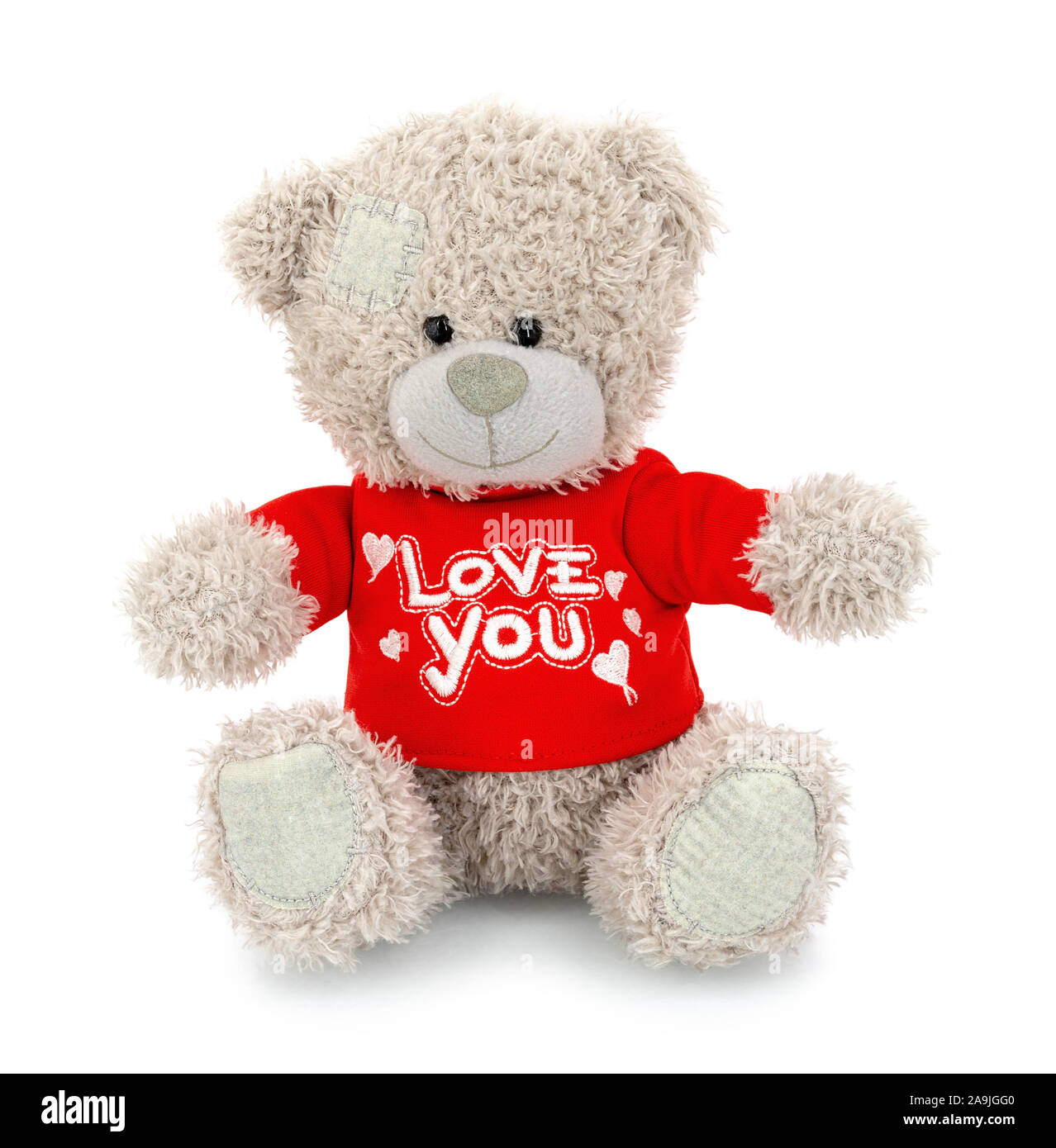 Cute bear doll with red LOVE YOU shirt isolated on white background with shadow reflection. Playful bright brown bear sitting on white underlay. Teddy Stock Photo
