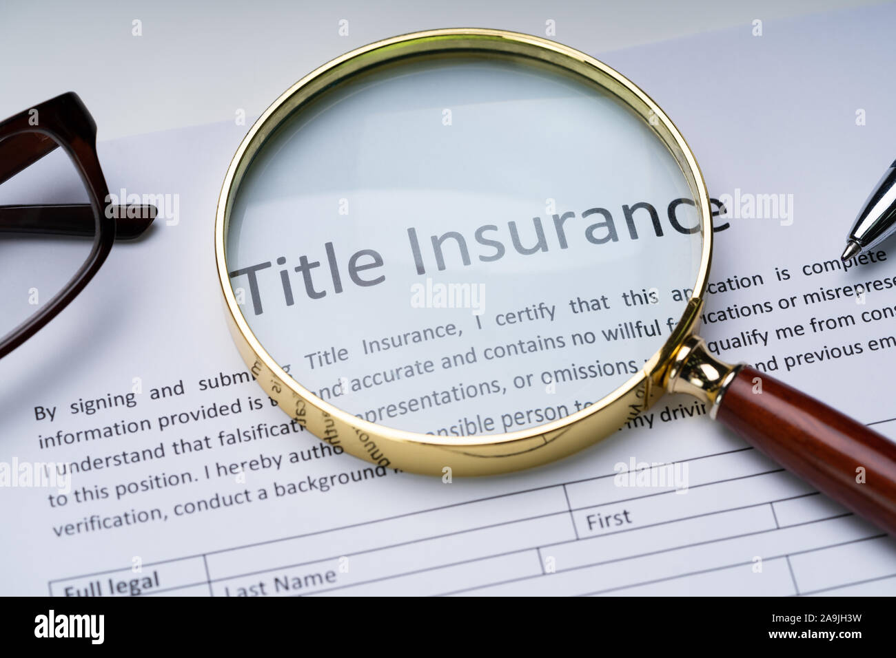 Magnifying Glass Over Title Insurance Form On Table Stock Photo