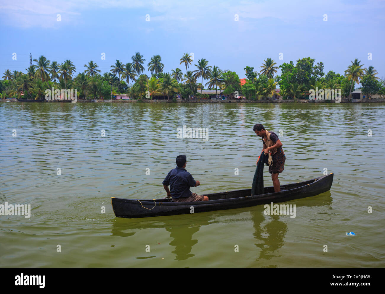 Two fishermen fishing from a wooden canoe in Alleppey backwaters (Kerala, India) Stock Photo