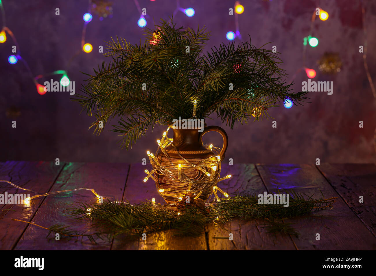 Vase with spruce branches stands on the table. Stock Photo
