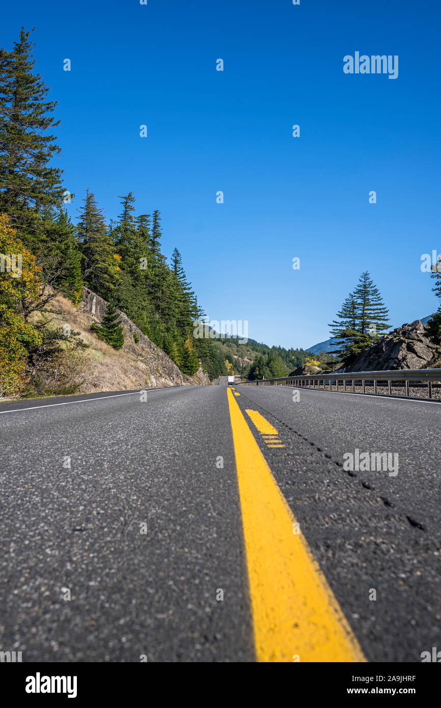 A mesmerizing landscape that attracts tourists with a winding road with road sign around a rock cliff on one side and an abyss on the other side in th Stock Photo