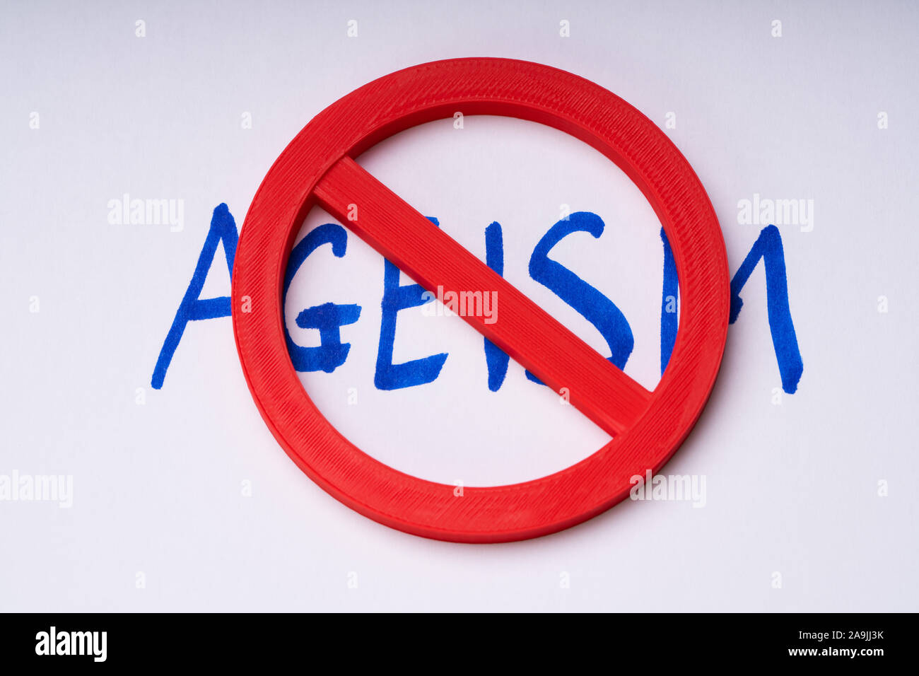 Red Stop Sign On Handwritten Ageism Text Over White Backdrop Stock Photo