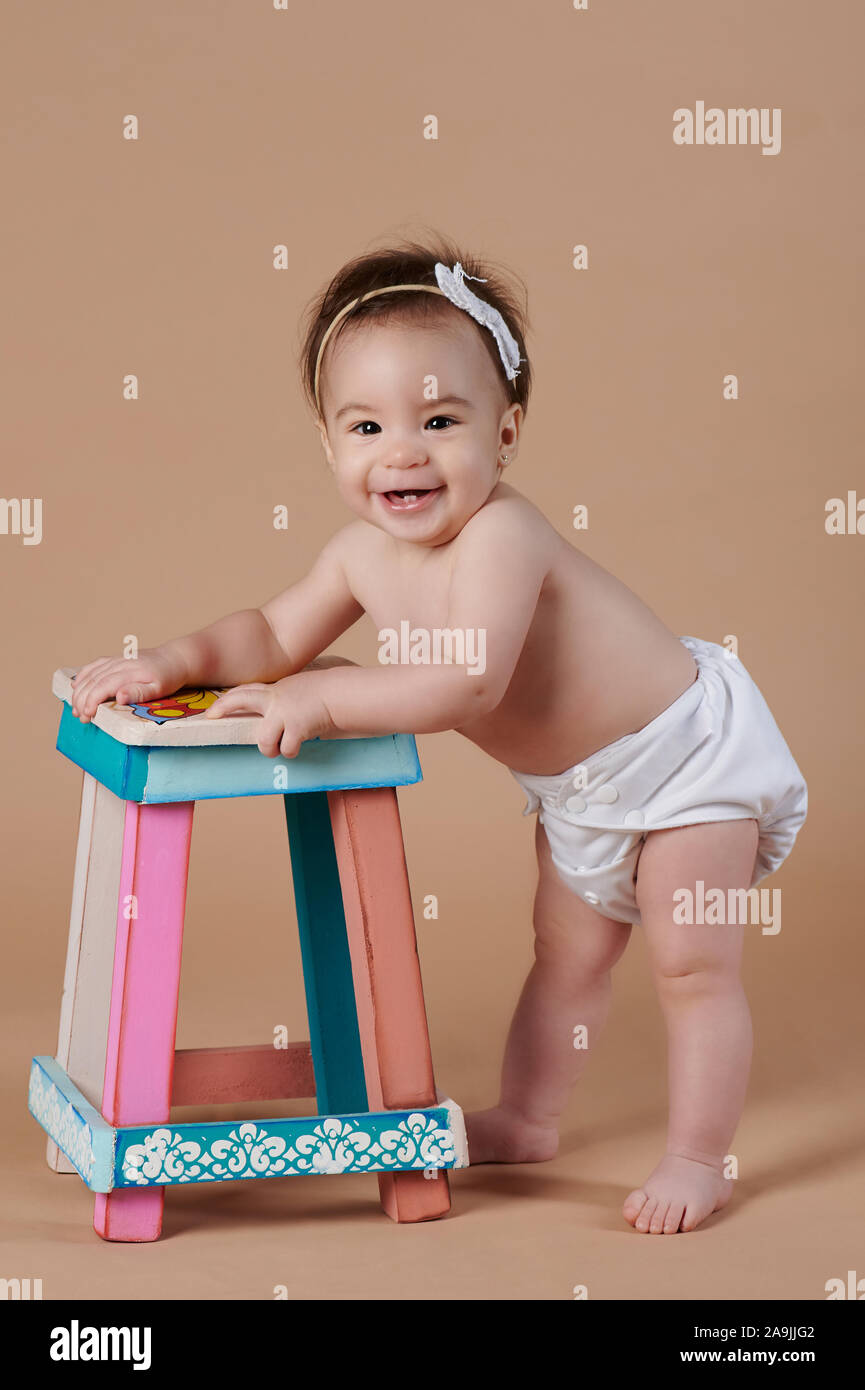 One little baby girl standing with kids chair on studio background Stock  Photo - Alamy