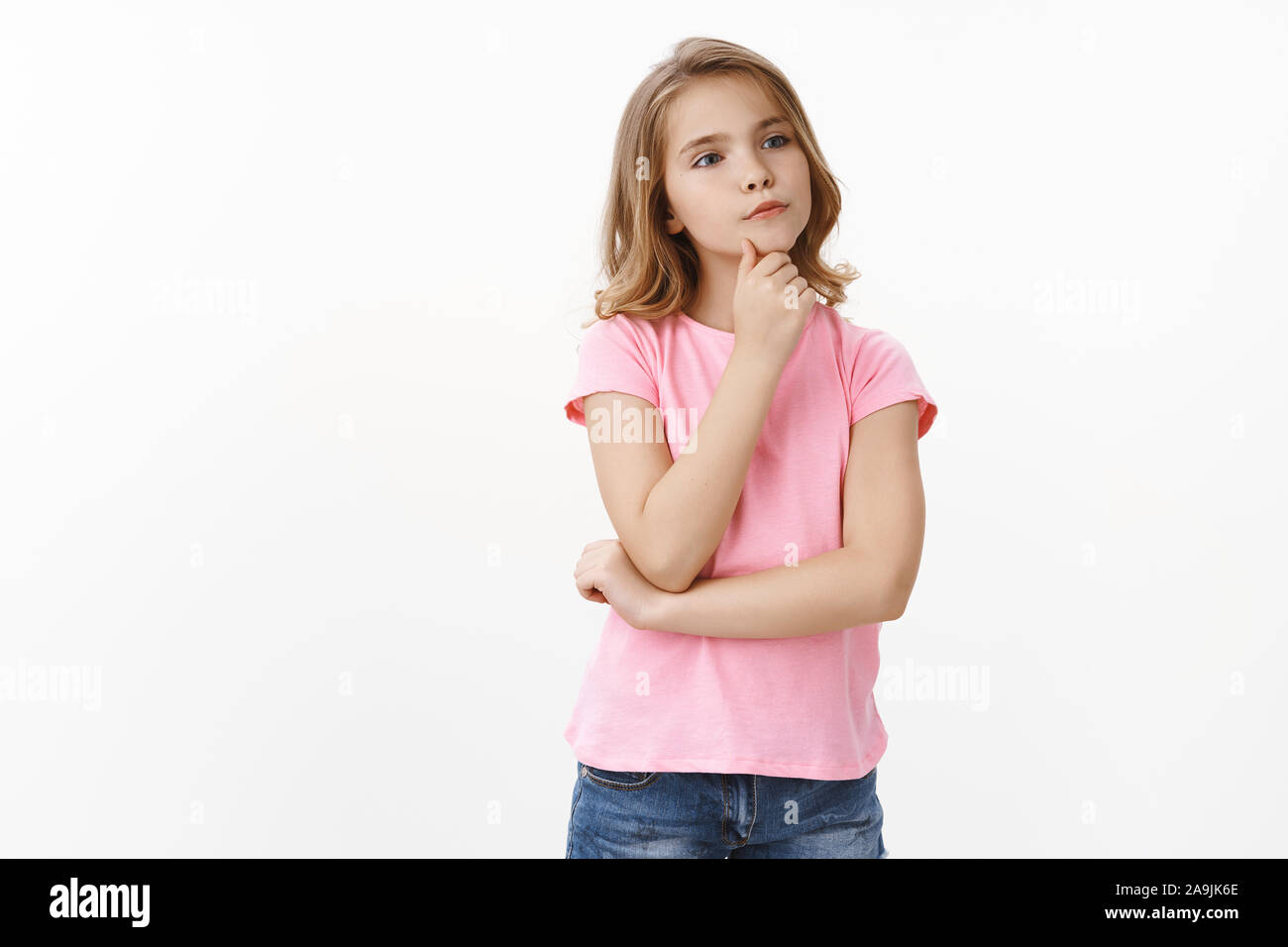 Curious smart and nosy creative blond little kid, thinking how solve situation, touch chin thoughtful, smirk focused look sideways copyspace, ponder c Stock Photo