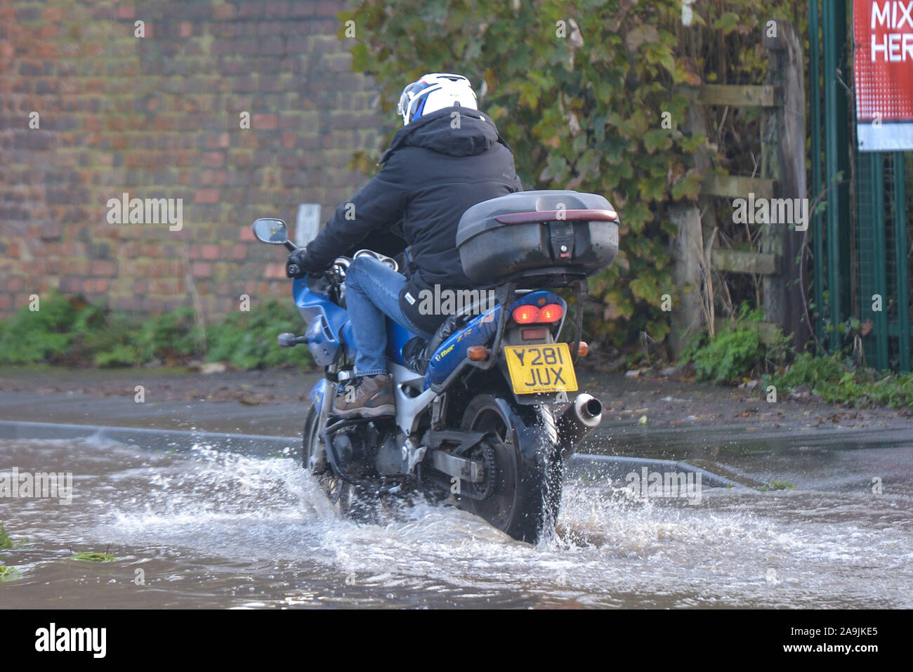 Tewkesbury, Gloucestershire UK. 16th November, 2019. A Motorbike rider lifs his legs as he navigates his way through floods in Tewkesbury town center which has been hit by severe flooding as the River Avon has burst its banks. River levels continue to rise and are expected to peak at over 12 meters above normal river levels late on Saturday afternoon. Pic taken 16/11/2019. Credit: Sam Holiday/Alamy Live News Stock Photo
