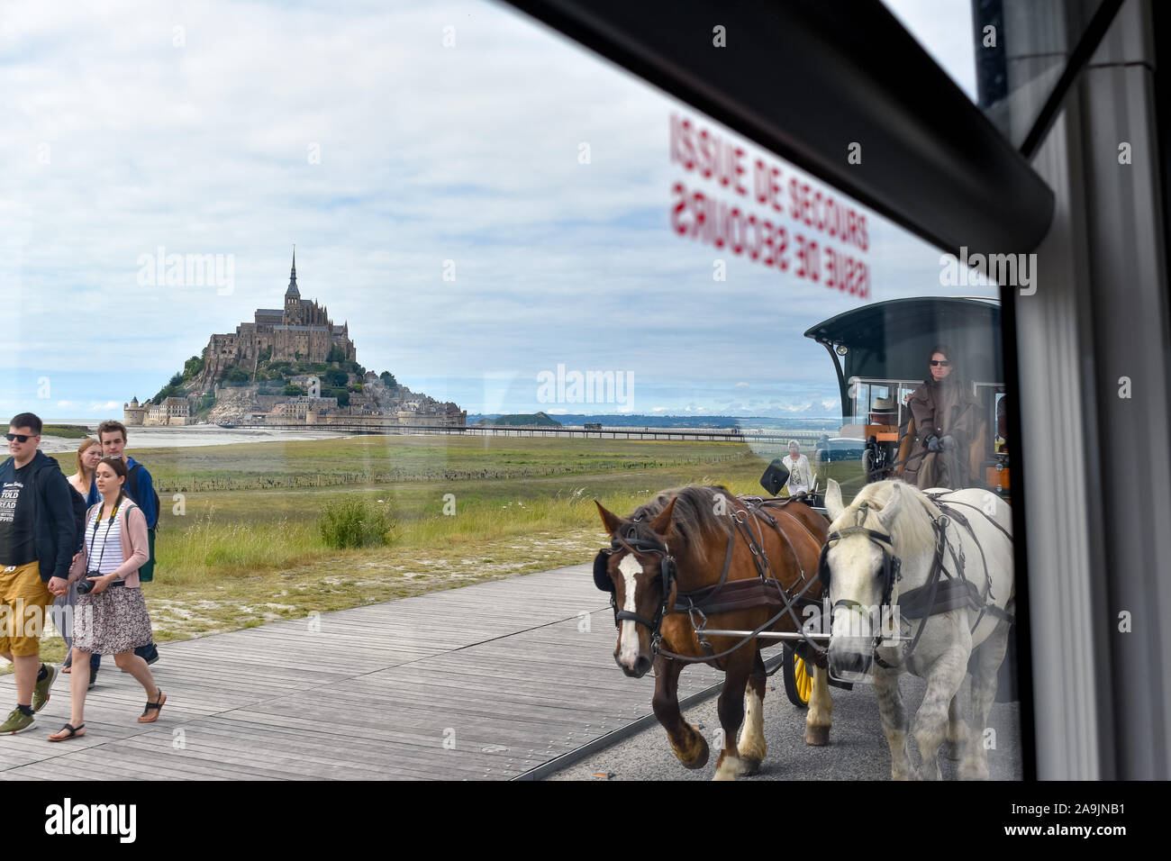 MONT SAINT-MICHEL, FRANCE - JULY 3, 2017: Tourists can choose different means of transportation, walking, bus or horse-drawn carriage. It is not possi Stock Photo