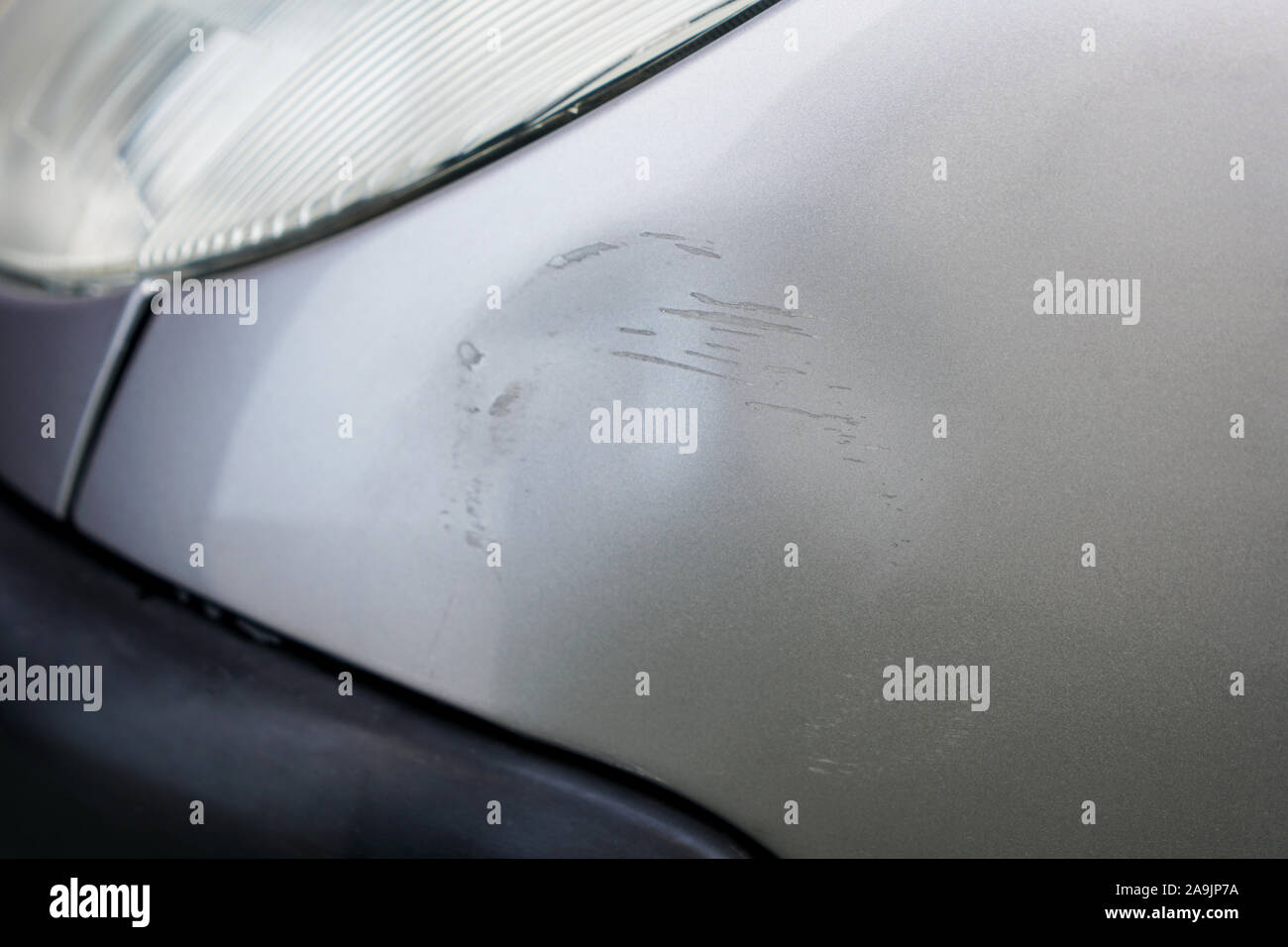 Macro of fender bender on silver gray car with scratches. Car with damage from crash accident, parking lot or traffic. Stock Photo