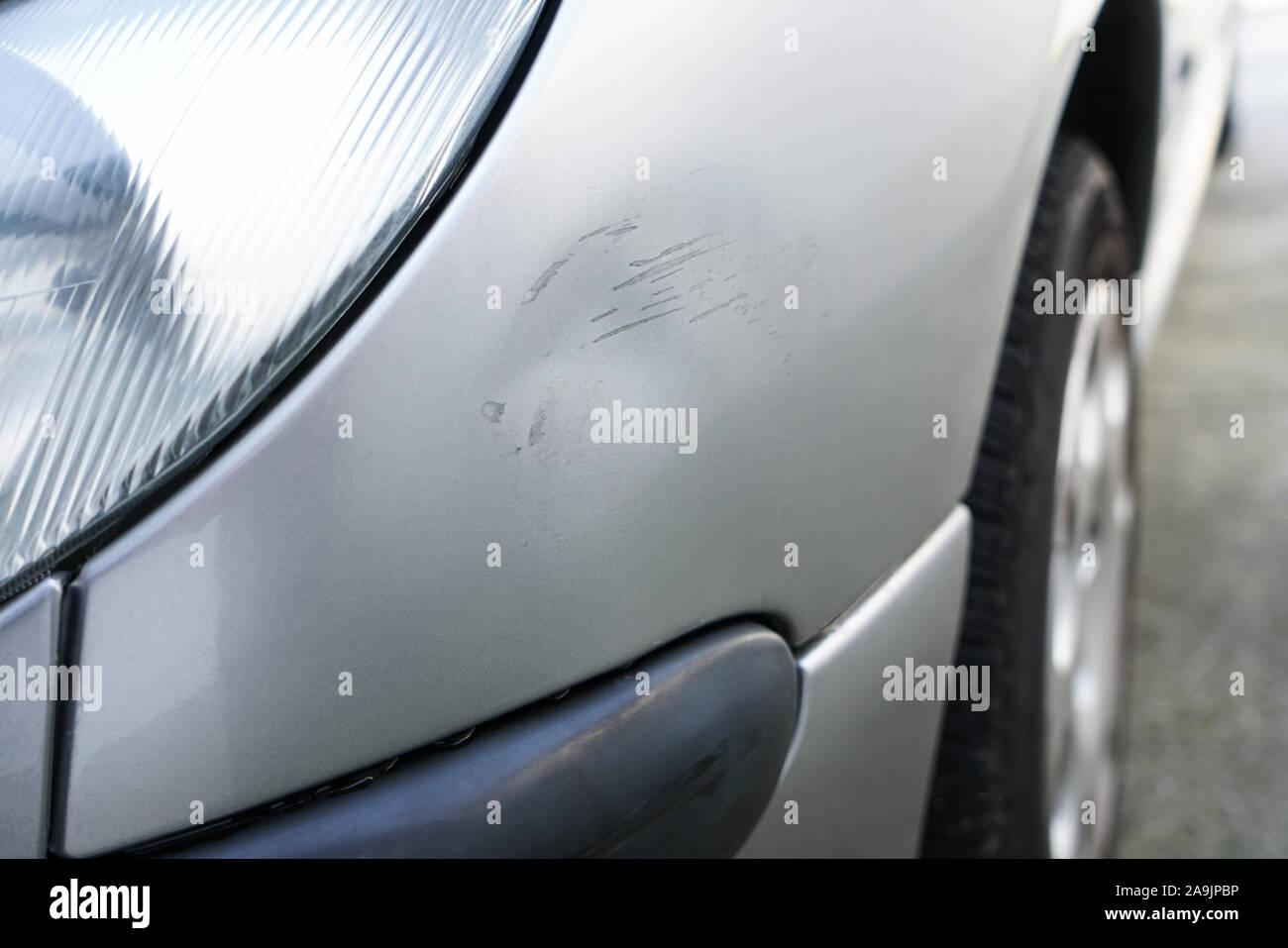 Close up of dent and scratches on side of old silver gray car. Damage from crash accident, parking lot or traffic. Stock Photo