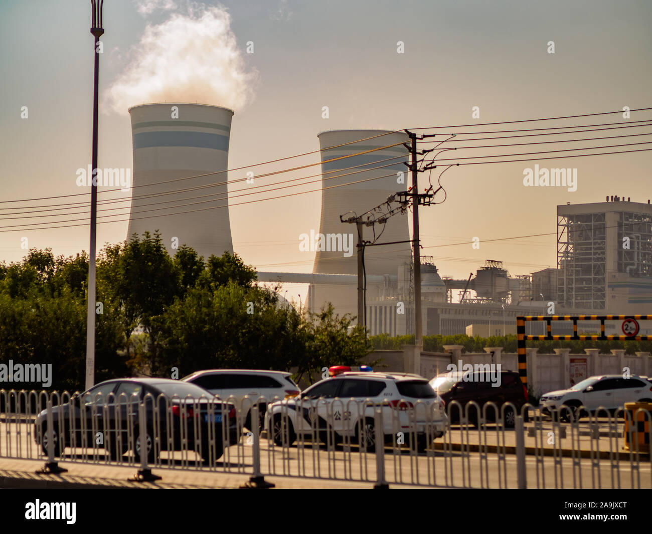 TIANJIN, CHINA - 7 OCT 19 - A  nuclear power plant next to a motorway emits a plume of white smoke from its smokestack. Stock Photo