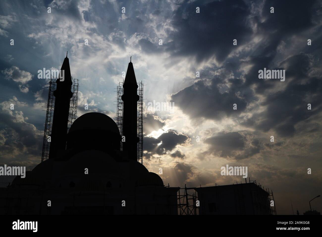 Kuwait City/Kuwait - 10/10/2019: Mosque under construction with minarets in scaffolding silhouetted against a cloudy sky Stock Photo