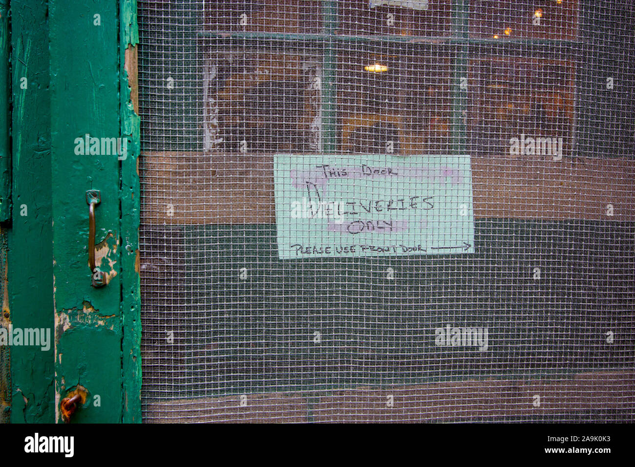 A Homemade Sign About Deliveries Only In A Screen Door At A