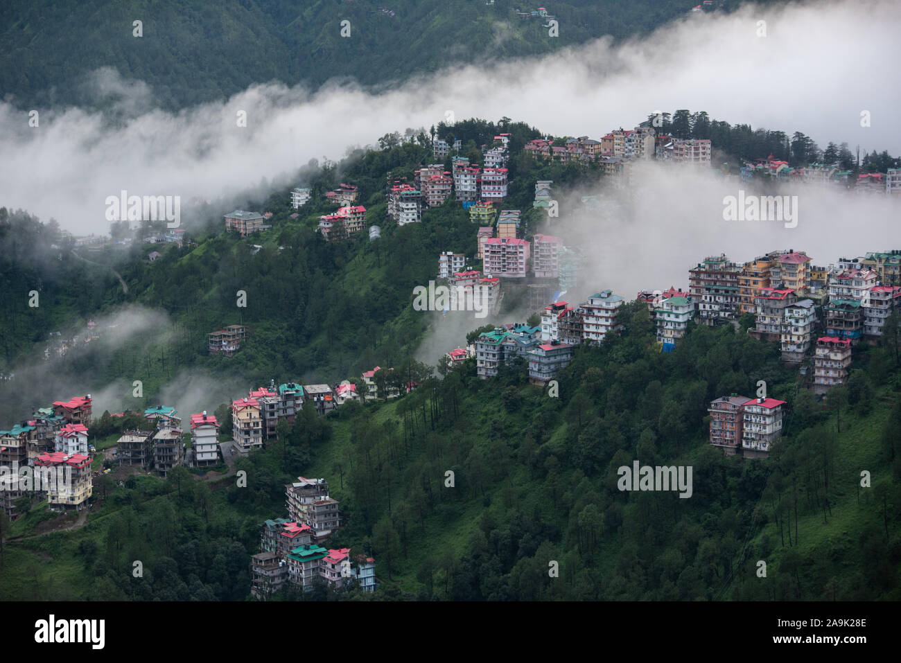 Buildings dotted on the misty mountains during the monsoon season in the Himalayas. Hills around Shimla, Himachal Pradesh, India Stock Photo