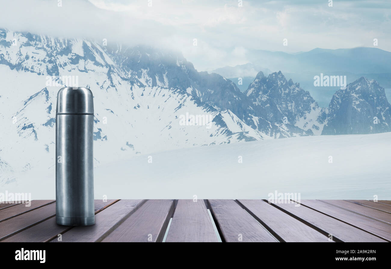 https://c8.alamy.com/comp/2A9K2RN/thermos-with-tea-or-coffee-and-landscape-of-mountains-on-background-hot-drink-on-wooden-table-with-snowly-and-cloudly-sky-warm-in-winter-day-holidays-travel-new-year-and-christmas-time-2A9K2RN.jpg